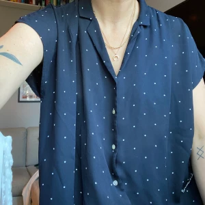 Prickig blus från Bondelid - Mörkblå blus med knappar och broderad logga vid sömmen längst ner. Fint skick! Frakt tillkommer