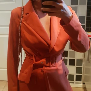 Orange kavajklänning - Klänning i kavajpassform. Dubbelknäpt med tryckknappar och brett bälte.