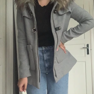 Kappa med luva och päls  - Säljer en jätte fin grå kappa från Dennis Maglic. Den är lite nopprig, skriv för fler och närmare bilder. Pris går att diskuteras. Det är storlek XS Ny pris 1799 kr. ( frakt ingår ej )  