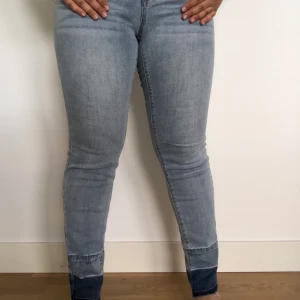 Gråa Jeans med blå detalj - HELT NYA OANVÄNDA! Säljer superstretchiga, högmidjade och jättesköna jeans i en kall, grå färg. Säljer då jag fick de som present och de inte är min stil. Jättefin passform som framhäver former och underbart skönt material som kan vikas på kanterna. Frakt ingår ej