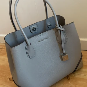 Michael Kors väska - Så fin grå väska från Michael kors. Använd så pass lite så den är som ny. Får plats med allt, necessär, dator, böcker mm. Säljer för att den tyvärr inte kommer till användning. Köpt förra sommaren i butiken för ca 1900kr. Pris kan diskuteras.