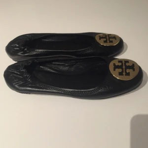  - Tory Burch ballerina skor i svart skin och guld med resår bak. Väldigt fint skick. 
