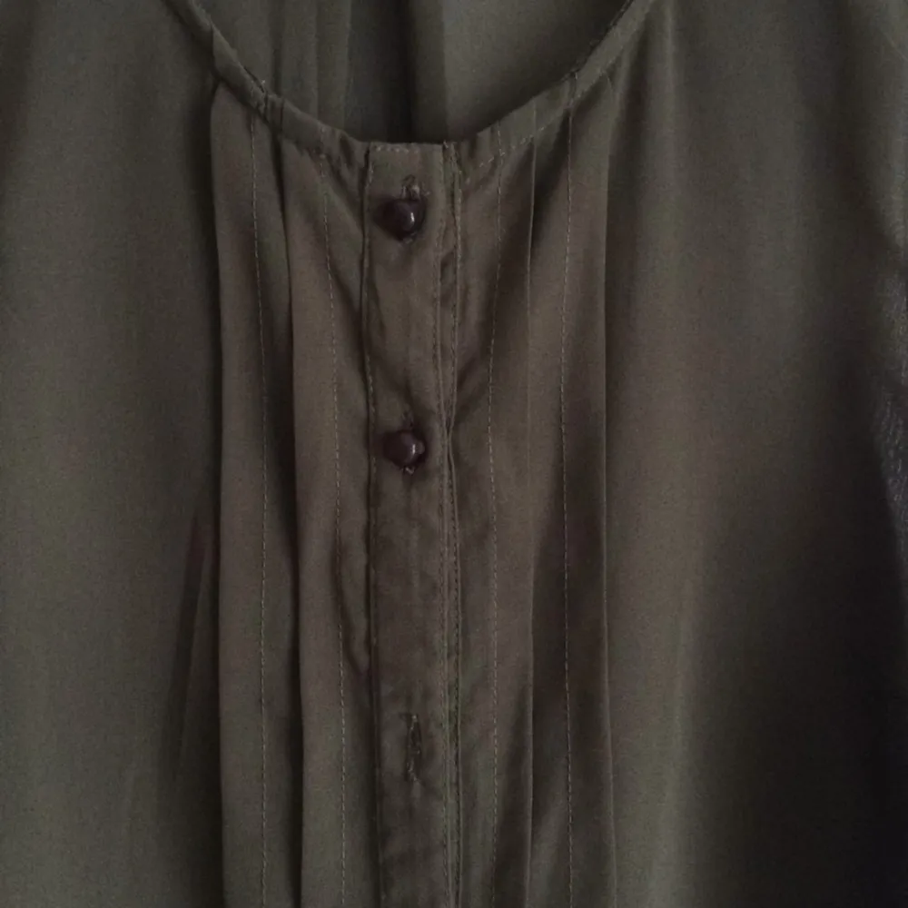 Mörkgrönt transparent linne från vila. 
Bortklippt lapp och en knapp saknas. 
Använt en gång.. Toppar.