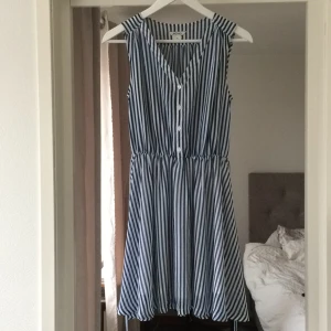  - Vacker klänning från Monki. Blå-vitrandig med resår i midjan samt ett litet band. Passar även S. Aldrig använd!