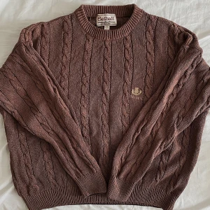 Tröja - Brun kabelstickad tröja med märke på bröstet. Materialet har blivit lite ”stelt” från tvätt. Men annars fläckfri. Strl L men är liten i storleken