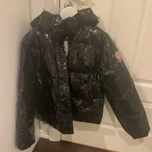 Helt ny glansig jacka - Helt ny svart glansig jacka från boohoo. Storlek 38. Alla lappar kvar och endast testad. Köpt för 1010kr.