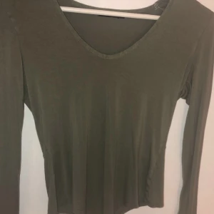 Nelly grön body  - Grön body med urringning från Nelly. I storlek M men passar även S. I använt skick men fortfarande fin. Kan hämtas på Alnö men kan även skickas, köparen står för frakt. Rök och djurfritt hem👍🏻