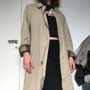 Trenchcoat - Rejäl trenchcoat med skotskrutig insida! Väldigt stor, så nästan alla kan ha den, men den passar på mindre personer också (jag är en xs och tycker det är snyggt med oversizen!) sömmen har spruckit i armhålorna, men annars bra skick. 