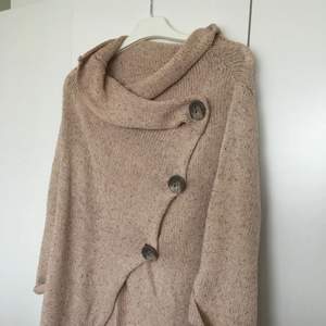Ljusrosa stickad tröja från Gina Tricot. Stora dekorativa gråa knappar vid knäppning och på ärmar. Längre modell. 