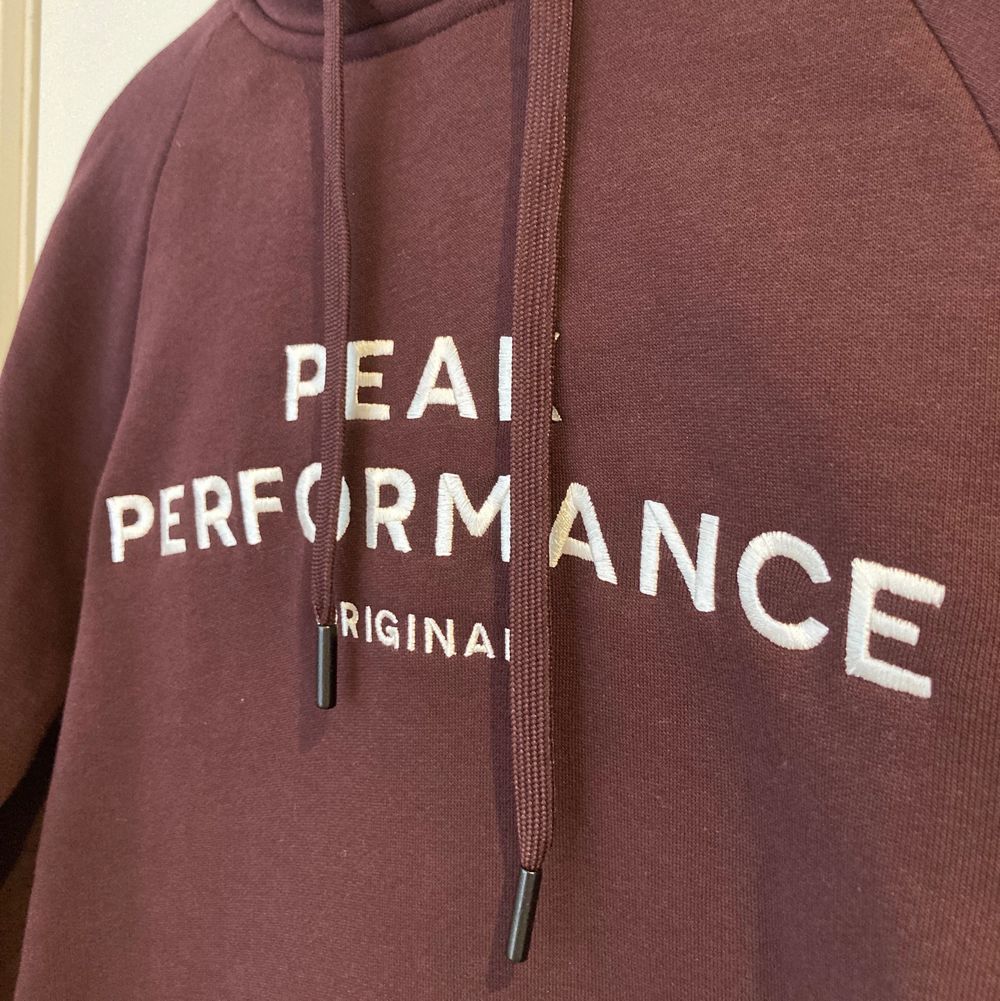 En vinröd hoodie från PeakPerformance med flis på insidan. Färgen syns bäst i första bilden.  Har aldrig använts. 80% bomull, 20% polyester . Huvtröjor & Träningströjor.