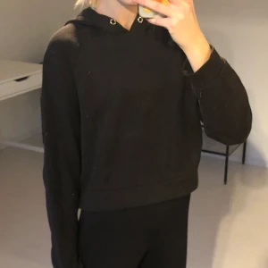 Svart hoodie - Kort svart hoodie. Tyvärr är snörena borttappade, men man kan sätta dit nya.