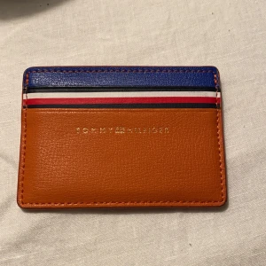 Tommy hilfiger - INTRESSEKOLL på denna korthållare ifrån Tommy hilfiger, köpt för 700kr i en Tommy hilfiger butik i Spanien. Den är äkta och i ett helt ypperligt skick!! Knappt använd över huvud taget!🧡 budgivning i kommentarerna.