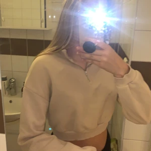 Cropad beige tröja - Säljer denna skitsnygga tröjan ifrån Nelly! Den är cropad och har en dragkedja vid halsen som man kan justera själv! Säljer då den inte kommer till användning!