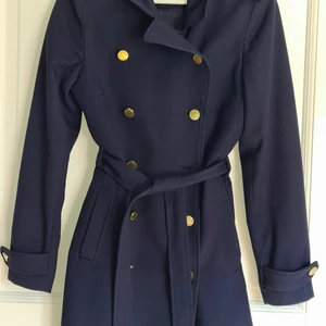 Blå kappa med guldkanppar  - 2 år gammal och i fint skick. Midjeband runt midjan samt två fickor.