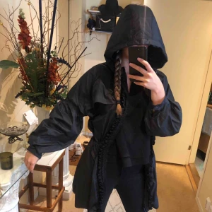  - Regnjacka med volanger från Adidas Stella McCartney. Nyskick! Supertrendig och fin! Kan dras åt i midjan. Stora fickor och stor luva. Stöter bort vatten. Storlek: 40, men passar 36 om man gillar oversize fit.