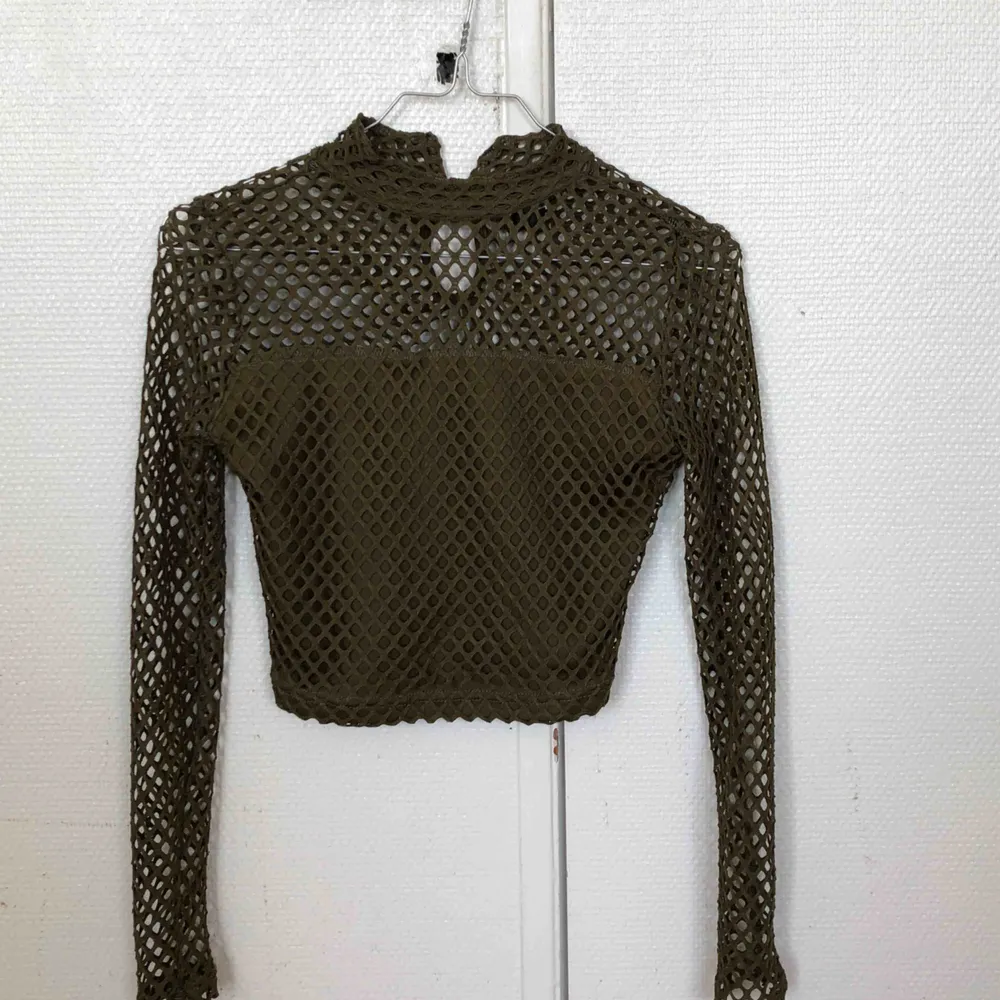 Mesh material, tight, with a slight turtleneck vibe, the arms are well fitted, crop top. . Toppar.