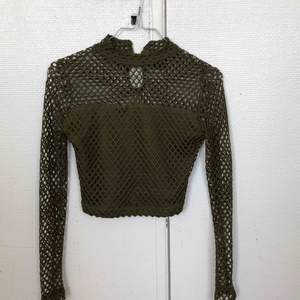 Mesh material, tight, with a slight turtleneck vibe, the arms are well fitted, crop top. 