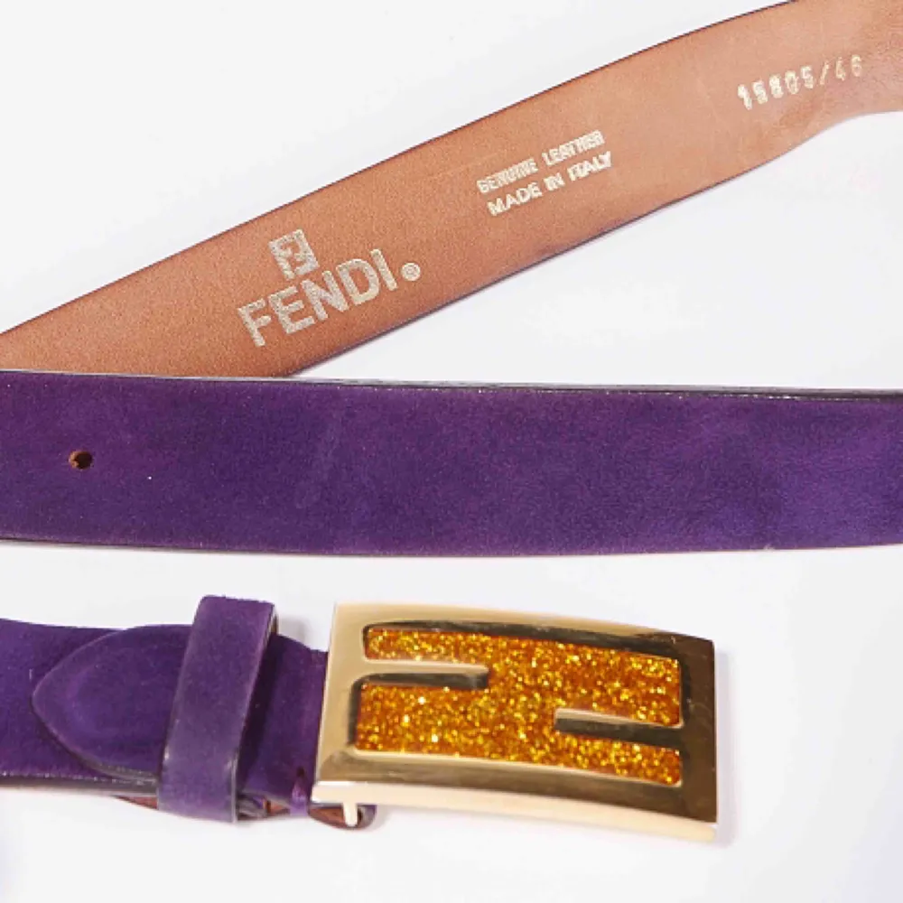 Vintage Fendi logo skärp i ametist lila mocka. Spännet är i guldmetall med saffransfärgat glitter. Skärpet är i fint skick med endast några få slitningar (se bilder)  Längd: 83-93 cm Bredd: 3 cm. Accessoarer.