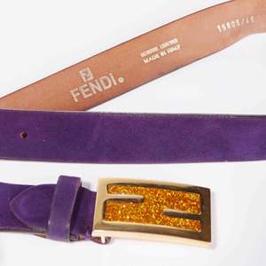 Vintage Fendi logo skärp i ametist lila mocka. Spännet är i guldmetall med saffransfärgat glitter. Skärpet är i fint skick med endast några få slitningar (se bilder)  Längd: 83-93 cm Bredd: 3 cm