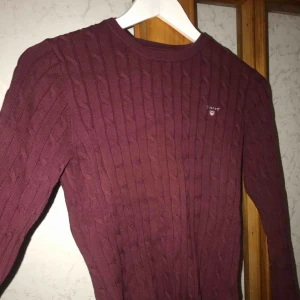  - Vinröd kabelstickad tröja från Gant. Använd fåtal gånger och är i otroligt bra skick, känns som ny. Säljer pga att det inte är min stil, men superfin höst färg! Nypris: 1200