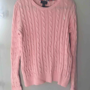  - Säljer en kabelstickad tröja från Ralph Lauren. Den är i barnstorlek XL vilket passar som vuxenstorlek XS/S. Det är en rosa tröja köpt för 1000kr men är aldrig använd. 