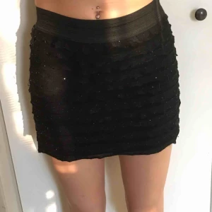  - Svart kjol med glitterdetaljer och volanger. Använd 1 gång. Fint skick.