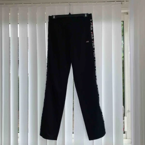  - Fila träningsbyxor med straight leg och revär på sidorna. Tjocka och varma byxor med resår i midjan. 