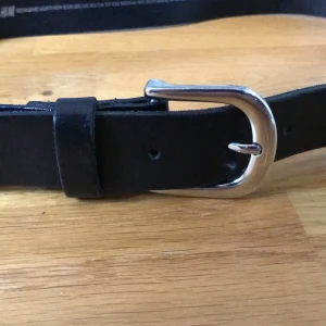 Svart skärp - XS från H&M. Basic stilrent läderskärp med silverspänne tillverkat i Sverige. Bra skick.