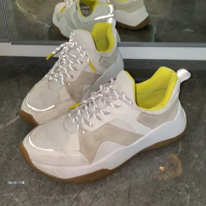 H&M Sneakers - Säljer snygga sneakers från H&M pga av fel storlek för mig. Beiga/ vita med gula detaljer. 