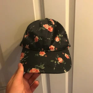 Monki keps - Jättesöt blommig monki keps som inte säljs längre. Den är sparsamt använd och i fint skick förutom små revor på framsidan (se bild 2) som knappt märks. Jag fraktar eller möts på Södermalm.  Nypris 120kr. 