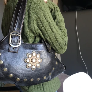 Svart väska  - Jätte fin svart väska med ascoola detaljer. Köpt second hand men aldrig använd. Den e i superbra skick, inga hål fläckar ect.