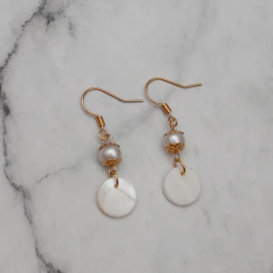  - Fina guldfärgade örhängen med pärlor av äkta snäckskal. Nickelfria.  Obs! Örhängena är inte orangea som på bilden, Photoshop ändrar färgerna för mig 🙃