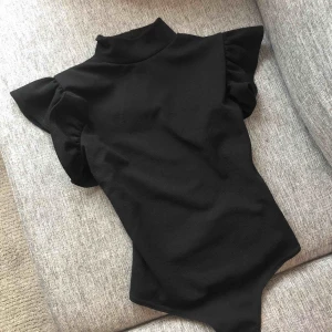  - Svart body med volang detaljer runt axlarna och hög krage. Provad 1 gång, aldrig använd.  Etiketten sitter fortfarande kvar.  Butikspris 250:-  95% polyester  5% elastan Frakt ingår. 