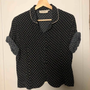  - Svart/mörkblå skjorta med guldblommor och guldkant på kragen. Köpt secondhand men märket är Lindex. Matchade den ofta med svarta jeans och Docs. Kan mötas upp i Stockholm, Västerås eller Uppsala. Betalning sker när vi ses!