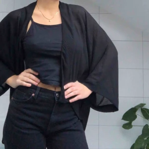  - En cardigan i svart, tunt material som passar som både vinterplagg och strandplagg. Går över rumpan och är väldigt skön att bära!
