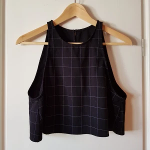  - Snygg crop top med öppen rygg. Knäpps med knapp i nacken. Tyget är lite grövre, rutmönstrat  och helt ogenomskinligt.