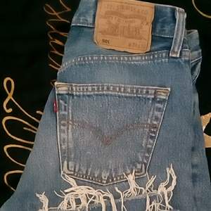 Blåa Levis 501 vintage med slitning nedtill på jeansen.