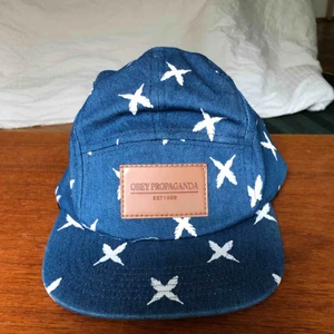  - Blå 5-panel keps med vita kryss. Justerbar rem där bak. Frakt tillkommer!