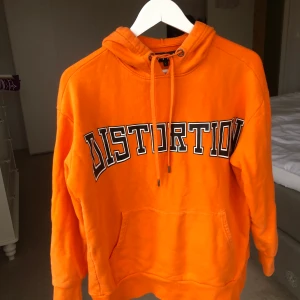 Carlings hoodie ”distortion” - Väldigt orange hoodie från carlings /stay, oversize och sjukt skön, storlek s men passar lätt en medium men skulle även se bra ut på mindre storlekar✨ i väldigt bra skick, nypris var runt 600kr