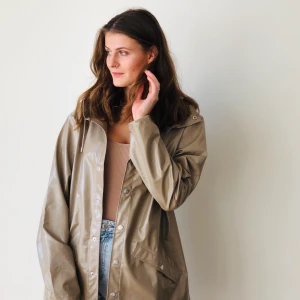 Beige color raincoat by Rains - Slightly oversized raincoat made by Rains - perfect to put a sweater underneath. Size: S/M, color: shiny holographic beige, has a hood.