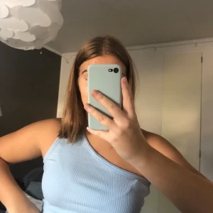 Topp 💙 - Ett fint one-shoulder linne i blått från Na-Kd, endast använt 2 gånger och är i fint skick! 💙💙 Storlek L men är inte så stort i storleken så skulle säga att det kan passa även S/M :) Köpare står för frakten 💙