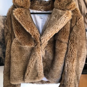 Fuskpäls jacka från H&M i brun/beige - En snygg fuskpälsjacka i väldigt bra skick som aldrig går ur mode! Den är lite oversized på mig som vanligtvis har S/M vilket blir sjukt snyggt! Jag är 170cm lång och på mig går den lite under midjan.