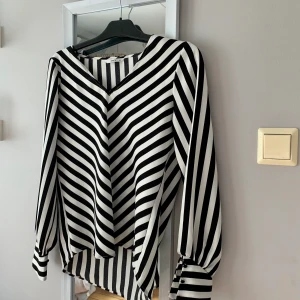 Randig blus från ONLY  - En svart-vit-randig blus i storlek 36 från ONLY som aldrig är använd 🤍🖤 väldigt fin urringning och knappar vid ärmen (frakt tillkommer och vid flera köpare blir det budgivning som avslutas 24 timmar efter första budet) 
