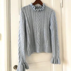  - Stickad ljusblå tröja (är mer ljusblå i verkligheten än på bilden) med volangärmar och i halsen 🌼