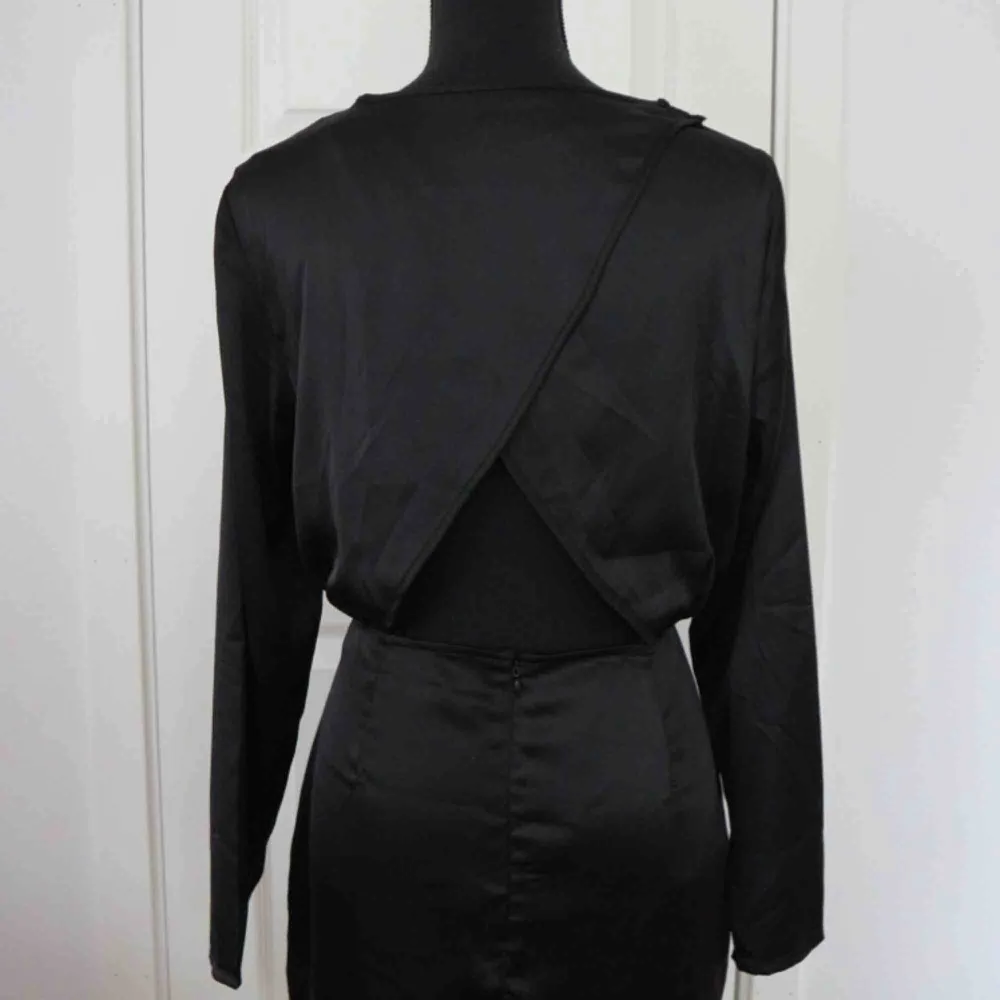Säljer en svart klänning i ett siden material med öppning i ryggen. Klänningen är i nytt skick! Storlek: 40 . Klänningar.