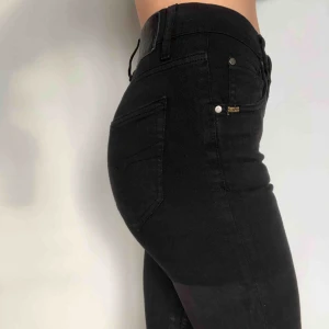  - Svarta jeans modell Kelly med lite blankare coating på benen från Tiger. Storlek 26 med stretch, sitter mycket bra och är sköna. Sparsamt använda.   Köparen betalar frakt, alt avhämtning i Gävle eller Uppsala! 