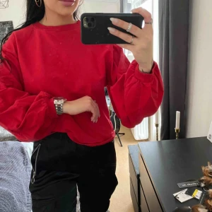  - En röd långärmad tröja, strl S. Med lite utsvängda ärmar. 