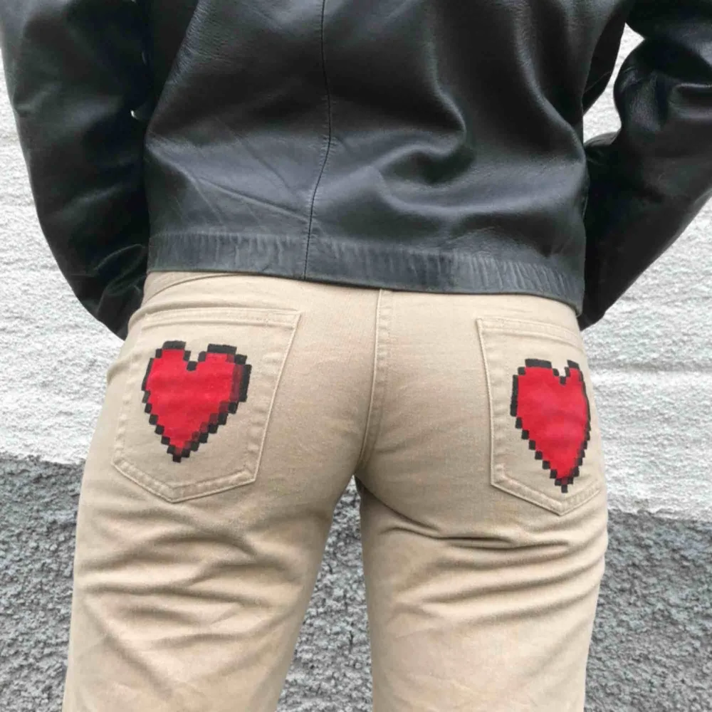 Supernajs beiga bootcut byxor med handmålade pixelhjärtan på bakfickorna och vid vristen!🕷 Modellen är 168 cm lång   . Jeans & Byxor.