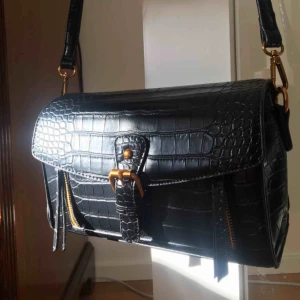  - Läderväska med gulddetaljer från Chiquelle🌸💕 Aldrig använd då jag fick 2 likadana. Väskan ligger fortfarande inpackad (på bilderna är den jag använder). Det är bra utrymme, 3 fickor och band som går att justera. Nypris 500kr.