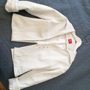 Sommarjacka i mjukt läder - Säljer vit läderjacka/blus. Den är jätte mjuk, långa ärmar som man kan vika eller rynka upp. Stängs med tre hyskor fram. Krage i 70-tals stil. Öppning/slits i ryggen.....Den har ett par skavanker från när jag ramlade med cykeln (se bild nr 3) 